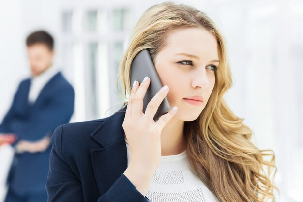 Retrato de mujer de negocios hablando por teléfono en la oficina