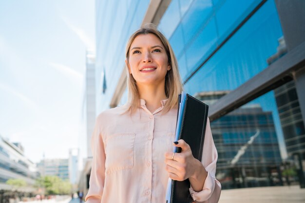 Retrato de mujer de negocios joven de pie fuera de los edificios de oficinas. Concepto de negocio y éxito.