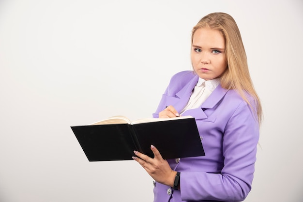 Retrato de mujer de negocios joven de pie y sosteniendo el portapapeles.