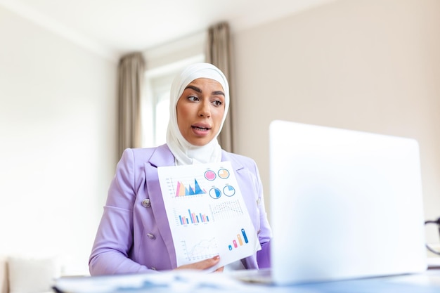 Retrato de una mujer de negocios musulmana que usa hiyab trabaja en un proyecto de ingeniería hace un análisis de documentos y planos Emprendedor digital empoderado trabaja en un proyecto de inicio de comercio electrónico