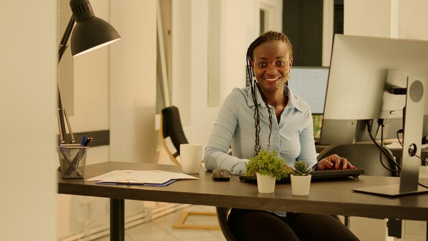 Retrato de una mujer de negocios que usa una computadora en el escritorio de la empresa, trabajando en datos de investigación y papeleo. Análisis de información en línea para hacer informes y tomar notas, envío de correo electrónico ejecutivo.