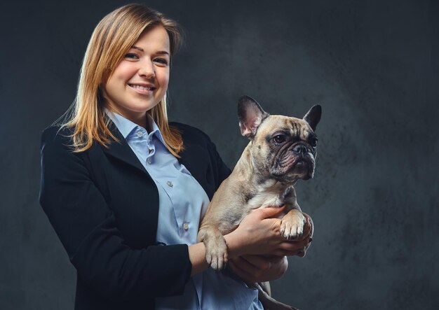 Foto gratuita retrato de una mujer de negocios rubia con traje formal sostiene un lindo perro