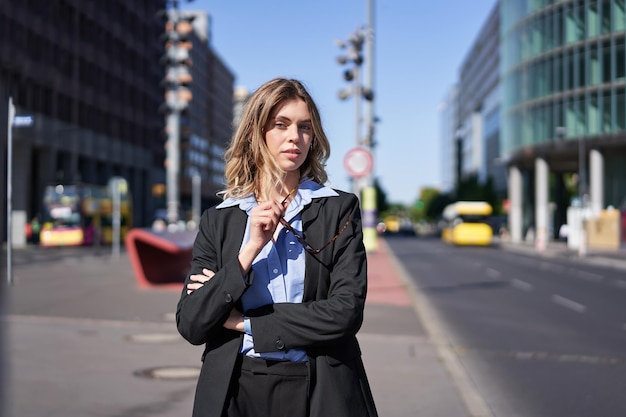Foto gratuita retrato de una mujer de negocios segura de sí misma con traje cruzado de brazos en el pecho que parece segura de sí misma en el centro de la ciudad