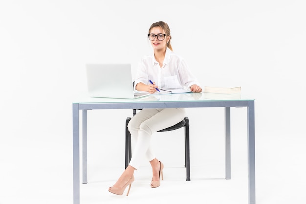 Retrato de una mujer de negocios sentado en un escritorio con una computadora portátil aislado sobre fondo blanco.