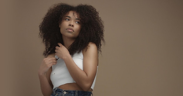 Retrato de mujer negra de raza mixta con pelo rizado de pelo afro grande en fondo beige