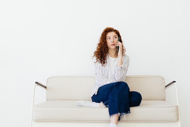 Retrato de una mujer pelirroja bastante joven hablando por teléfono móvil