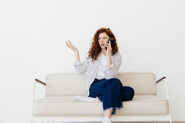 Retrato de una mujer pelirroja bastante joven hablando por teléfono móvil