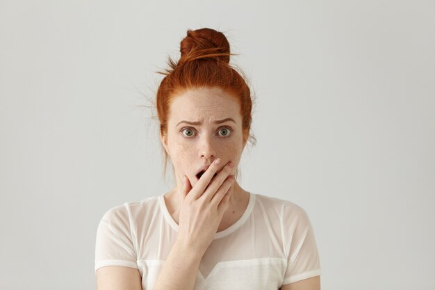 Retrato de mujer pelirroja joven atractiva asombrada sorprendida vistiendo top blanco