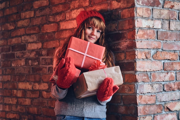 Retrato de mujer pelirroja con ropa de abrigo tiene regalo de Navidad.