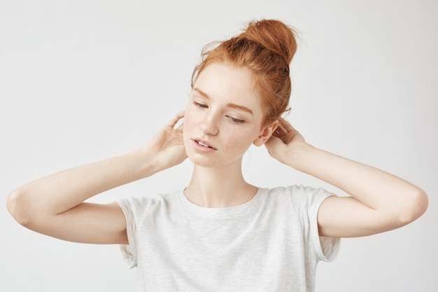 Retrato de mujer pelirroja tierna con bollo de pelo y pecas sonriendo.