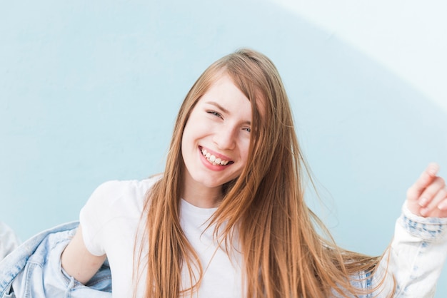 Retrato de la mujer del pelo rubio que sonríe en fondo azul