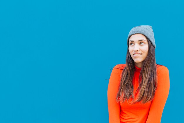 Retrato de mujer pensativa frente a superficie azul