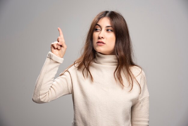 Retrato de mujer pensativa mostrando la dirección con el dedo índice.