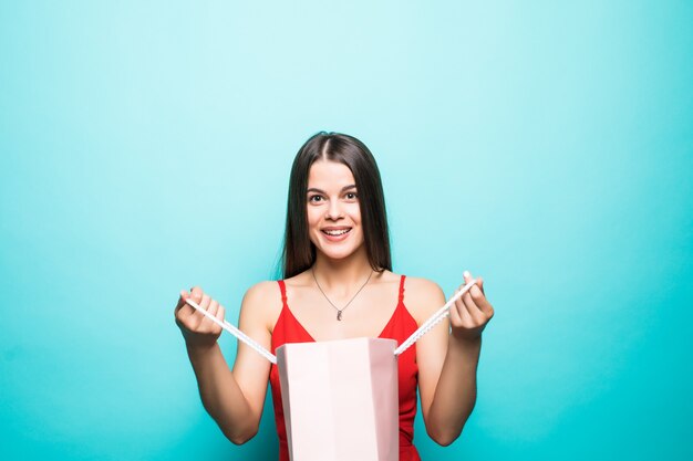 Retrato de una mujer pensativa sonriente sosteniendo bolsas de la compra y mirando a otro lado aislado sobre la pared azul