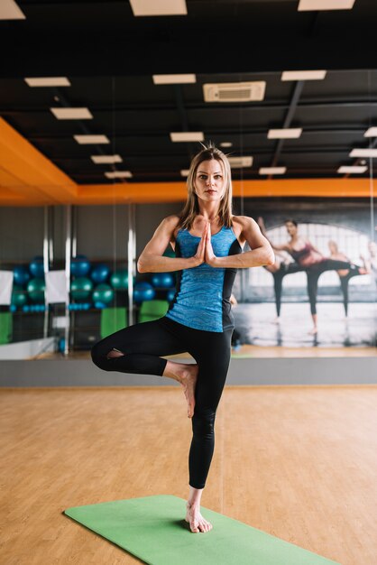 Retrato de mujer de pie en posturas de yoga en el gimnasio