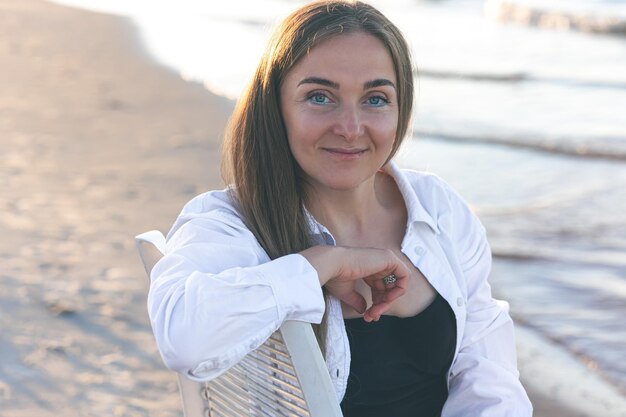 Retrato de una mujer en la playa con delineador de ojos azul sobre un fondo borroso