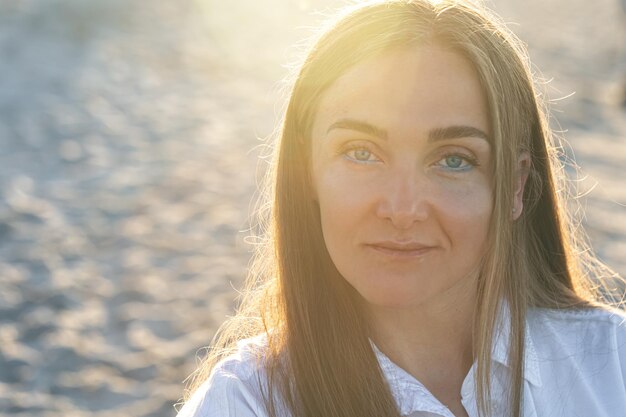 Retrato de una mujer en la playa con delineador de ojos azul sobre un fondo borroso