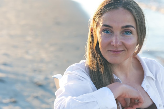 Retrato de una mujer en la playa con delineador de ojos azul sobre un fondo borroso