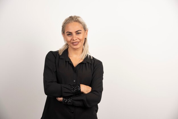 Retrato de mujer positiva en camisa negra posando sobre fondo blanco. Foto de alta calidad