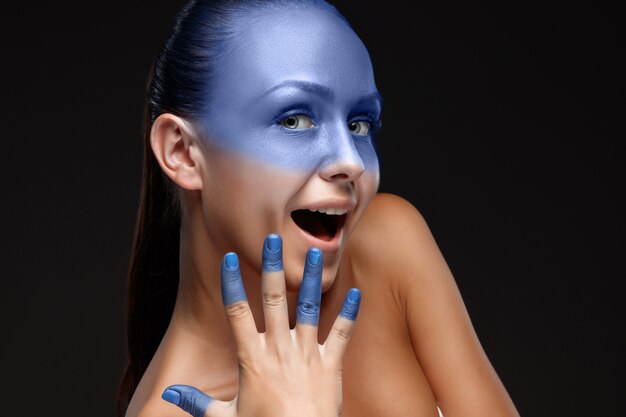 Retrato de una mujer que está posando cubierta con pintura azul