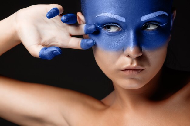 Retrato de una mujer que está posando cubierta con pintura azul