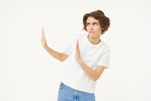 Foto gratuita retrato de una mujer que evita a alguien muestra un gesto de bloquear las manos y se niega a hacer algo malo