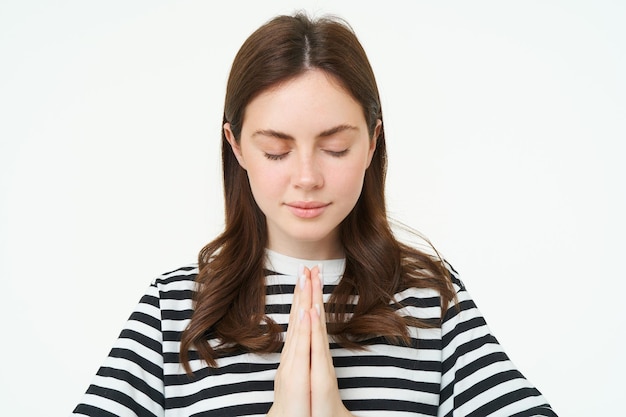 Foto gratuita retrato de una mujer que muestra el gesto de namaste sosteniendo las palmas apretadas cerca del pecho de pie