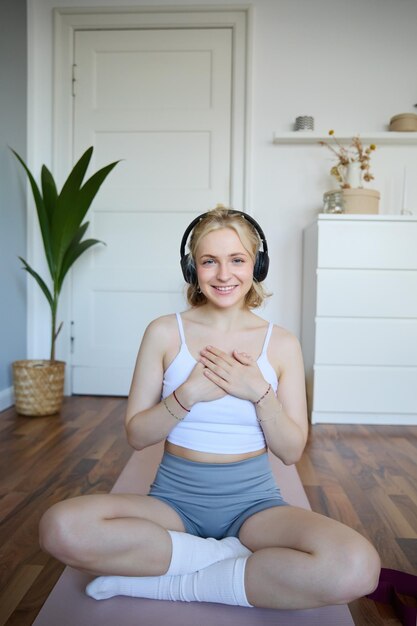 Retrato de una mujer que se siente relajada y en paz después de la meditación o el entrenamiento de yoga en casa sosteniendo