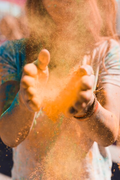 Retrato de una mujer quitando el polvo del holi con las manos