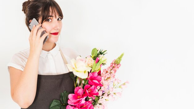 Retrato de una mujer con ramo de flores hablando por teléfono inteligente