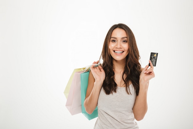 Retrato de mujer rica y moderna comprando compras y pagando con tarjeta de crédito, aislado en blanco