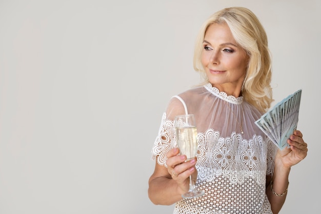 Retrato de mujer rica rubia de mediana edad con copa de champán y billetes