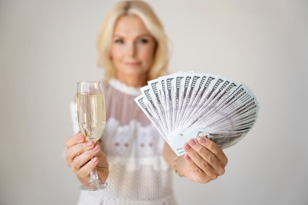 Retrato de mujer rica rubia de mediana edad con copa de champán y billetes