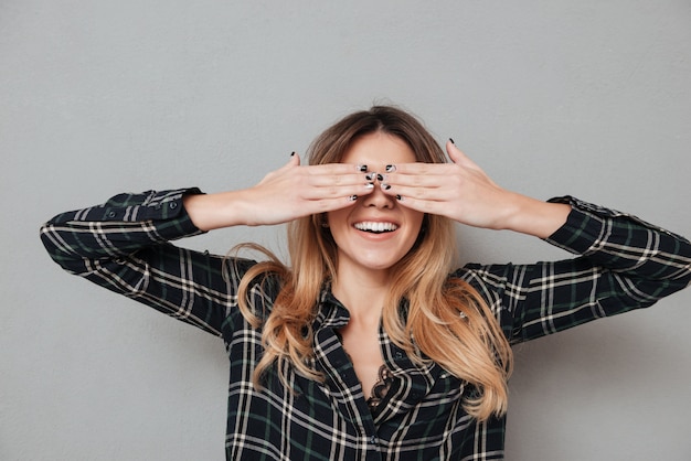 Retrato de una mujer riendo cubriendo sus ojos con las manos