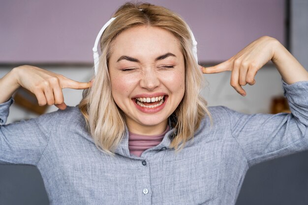 Retrato de mujer riendo y escuchando música con auriculares