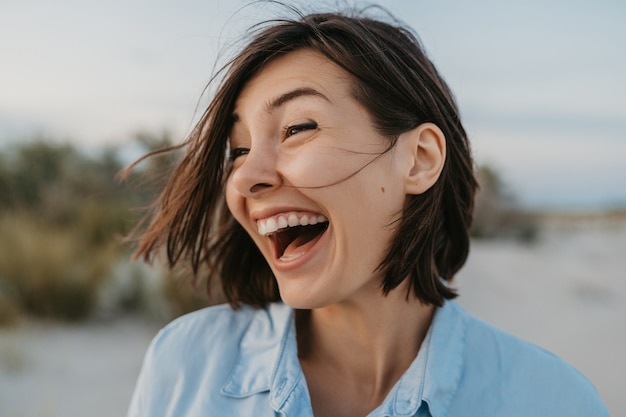 Foto gratuita retrato de mujer riendo sincera en la playa