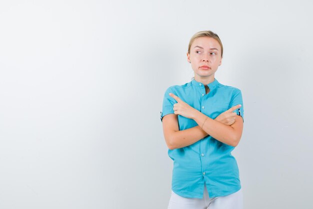 Retrato de mujer rubia apuntando a ambos lados en blusa azul aislado