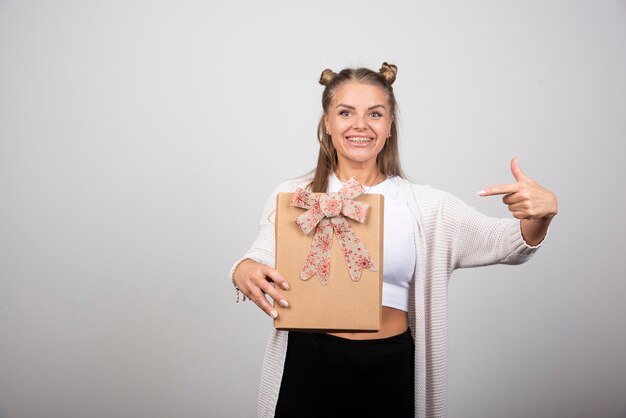 Retrato de mujer rubia apuntando a caja de regalo.