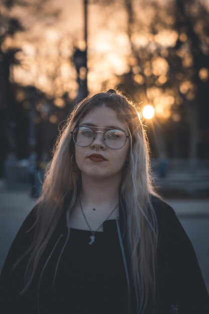 Retrato de una mujer rubia joven confiada con gafas y lápiz labial rojo