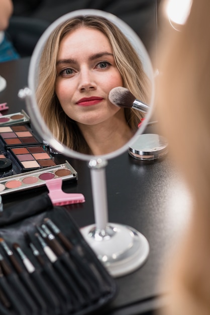 Retrato de una mujer rubia joven que usa los cosméticos