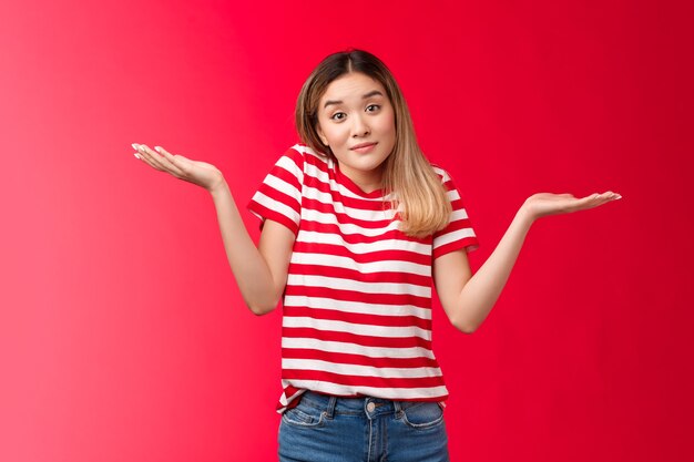 Retrato de mujer rubia relajada sin molestias encogiéndose de hombros con las manos extendidas hacia los lados ...