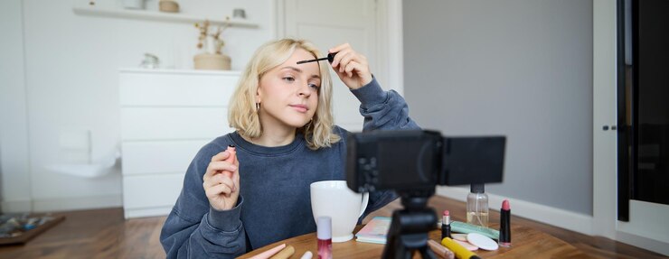 Foto gratuito retrato de una mujer rubia sonriente registra un vlogger de blog de estilo de vida o un artista de maquillaje grabando un video
