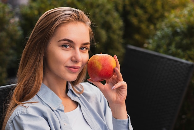 Retrato de mujer rubia sosteniendo una manzana