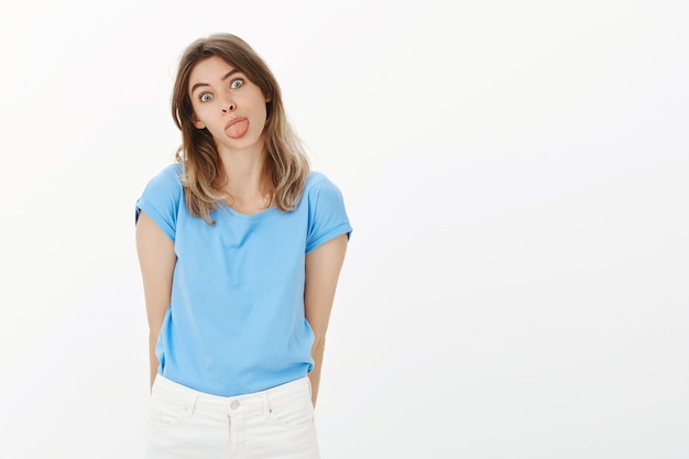 Retrato de mujer rubia tonta y divertida mostrando lengua infantil