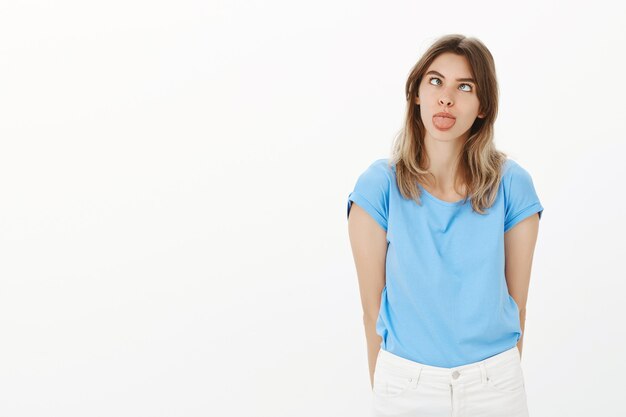 Retrato de mujer rubia tonta y divertida mostrando lengua infantil