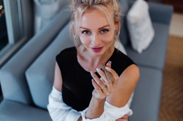 Retrato de mujer rubia en traje de cuerpo y camisa blanca con hermosos labios rosados con cigarro