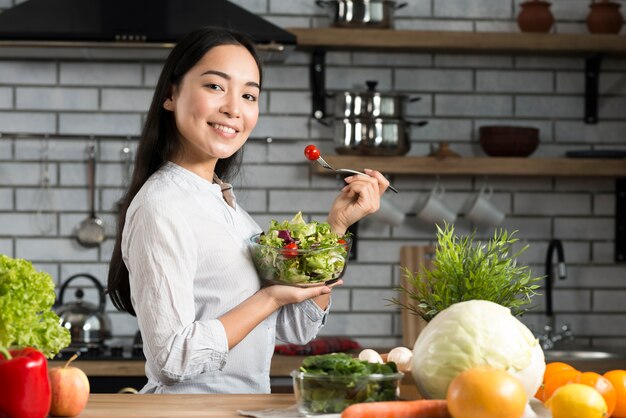 Retrato de mujer sana comiendo ensalada en la cocina