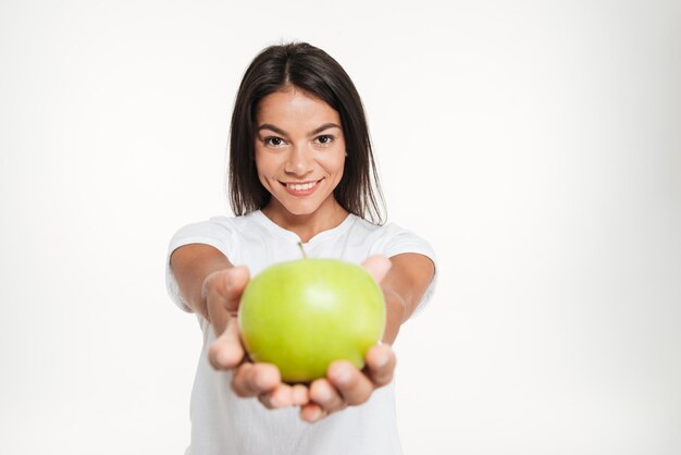 Retrato de una mujer sana sonriente mostrando manzana verde