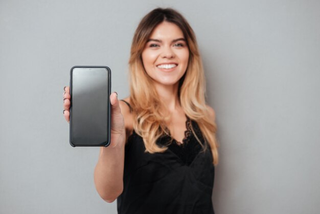 Retrato de una mujer segura mostrando teléfono móvil de pantalla en blanco