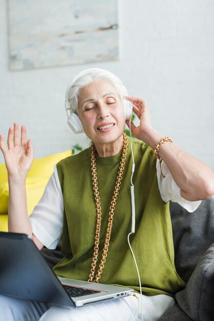 Retrato de mujer senior escuchando música en auriculares